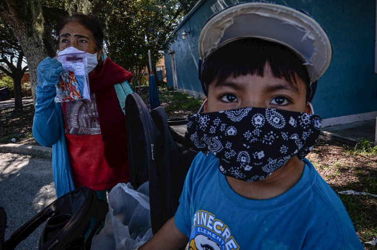 Esperanza Miranda y su nieto visten tapabocas para protegerse del contagio, el 17 de junio de 2020 en Immokalee, en el sur de la Florida. A costa de su salud miles de inmigrantes mexicanos y centroamericanos declarados "esenciales" lograron sacar este año la cosecha en Immokalee, la capital del tomate en EE.UU. y ahora también uno de los focos más candentes de la Covid-19 en Florida. Foto: Giorgio Viera/EFE.