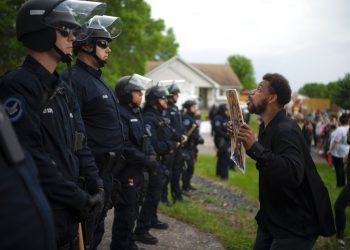 Un manifestante sostiene una pancarta mientras salta en repetidas ocasiones para que los policías que se encuentran al fondo puedan verlo el miércoles 27 de mayo de 2020 en la casa del agente Derek Chauvin, quien fue despedido de la policía de Minneapolis, a las afueras de Oakdale, Minnesota. Foto: Jeff Wheeler/Star Tribune vía AP