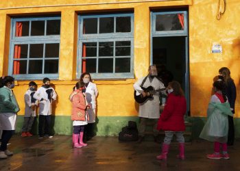 Usando una mascarilla en medio de la pandemia del nuevo coronavirus, un maestro le canta a su clase en el primer día de vuelta a la escuela rural cerca de Empalme Olmos, Uruguay, el lunes 1 de junio de 2020. Foto: Matilde Campodonico/ AP