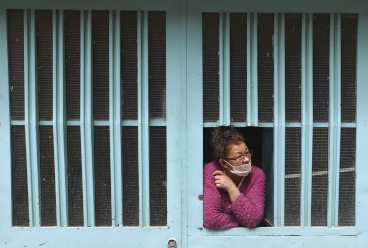 Una mujer observa desde la ventana de su casa mientras espera recibir comida gratis del gobierno de la ciudad el viernes 12 de junio de 2020, en Bogotá, Colombia, donde continúan las medidas de prevención por el coronavirus. (AP Foto/Fernando Vergara)