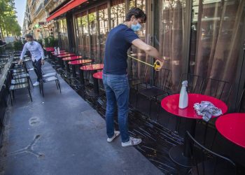 Pierre-Antoine Boureau con una cinta métrica instala las mesas en la terraza de un cadé en París, 1 de junio de 2020. Foto: Michel Euler/AP