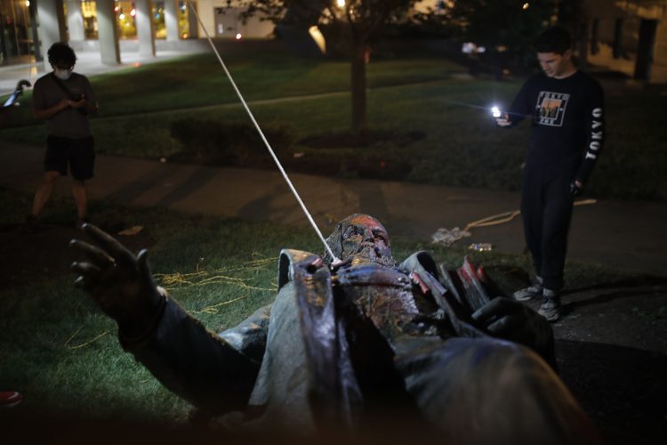 Un hombre usa su celular para grabar la estatua de Albert Pike, la única de un general del ejército confederado en la capital de Estados Unidos, después de que fue derribada por manifestantes e incendiada en Washington en las primeras horas del sábado 20 de junio de 2020. Foto: Maya Alleruzzo. AP