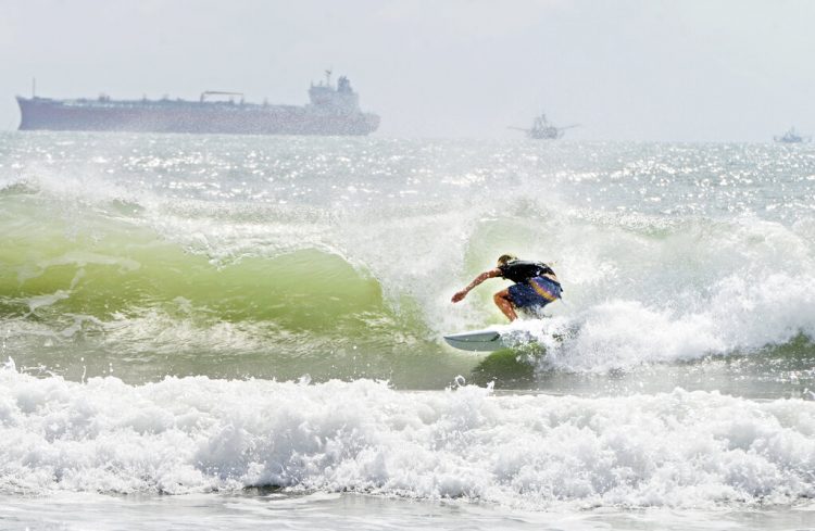 Un surfista se desplaza a orillas de la isla del Padre Sur el viernes 24 de julio de 2020 en medio de un mar picado debido a la tormenta tropical Hanna. (Miguel Roberts/The Brownsville Herald vía AP)