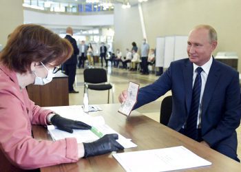 El presidente ruso Vladimir Putin muestra su pasaporte a una trabajadora electoral poco antes de votar el miércoles 1 de julio de 2020, en Moscú. Foto: Alexei Druzhinin/Sputnik vía AP.