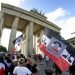 Personas con banderas con la cara del presidente estadounidense Donald Trump asisten a una manifestación contra las restricciones por la pandemia frente a la Puerta de Brandenburgo en Berlín, Alemania, el sábado 29 de agosto de 2020. (AP Foto/Michael Sohn)