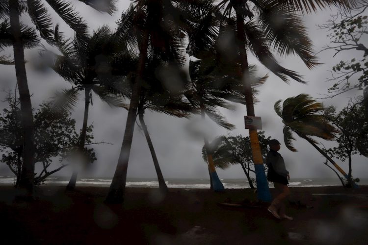 Una persona camina entre la lluvia y los fuertes vientos debido al paso de la tormenta Laura hoy, en Arroyo, sur de Puerto Rico. Foto: Thais Llorca/EFE.