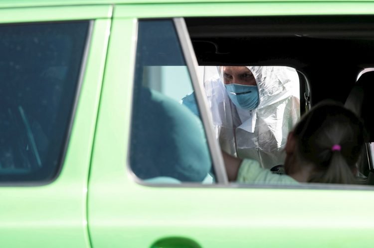 Un voluntario de la Cruz Roja Bávara realiza de manera gratuita la prueba para detectar la COVID-19 en un viajero. Cerca de Bergen, Baviera, Alemania, el 30 de julio de 2020. Foto: LUKAS BARTH-TUTTAS/ EFE/EPA.