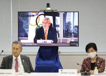 En esta imagen de archivo del 24 de septiembre de 2020, el presidente del COI, Thomas Bach, aparece en la pantalla para intervenir a distancia con el presidente del Comité Organizador Yoshiro Mori, a la izquierda, y la gobernadora de Tokio, Yuriko Koike, a la derecha durante una reunión virtual sobre los aplazados Juegos Olímpicos de Tokio, en Tokio. Foto: Du Xiaoyi/Pool via AP.