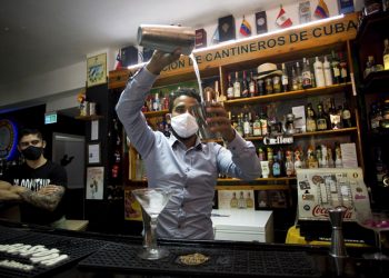 Con máscaras para protegerse del nuevo coronavirus, el bartender Dagoberto Jesús Morejón prepara un cóctel con plantas endémicas de Cuba, mientras su socio Manuel Alejandro Valdés lo respalda en La Habana, Cuba, el martes 13 de octubre de 2020. Foto: AP/Ismael Francisco.