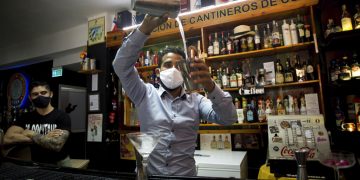 Con máscaras para protegerse del nuevo coronavirus, el bartender Dagoberto Jesús Morejón prepara un cóctel con plantas endémicas de Cuba, mientras su socio Manuel Alejandro Valdés lo respalda en La Habana, Cuba, el martes 13 de octubre de 2020. Foto: AP/Ismael Francisco.