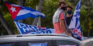 Unos jóvenes escuchan el discurso del ex presidente de Estados Unidos Barack Obama, sentados en el techo de un auto decorado con carteles que dicen "Cubanos con Biden Harris", durante un acto de apoyo al candidato demócrata a la presidencia Joe Biden, hoy, en el Campus Biscayne de la Universidad Internacional de Florida (FIU) en Miami, Florida. Foto: EFE/ Giorgio Viera.