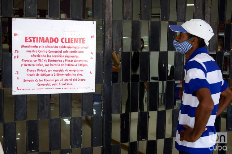 Un hombre lee un cartel colocado en la puerta principal del centro comercial Plaza Carlos III, en La Habana. Foto: Otmaro Rodríguez.