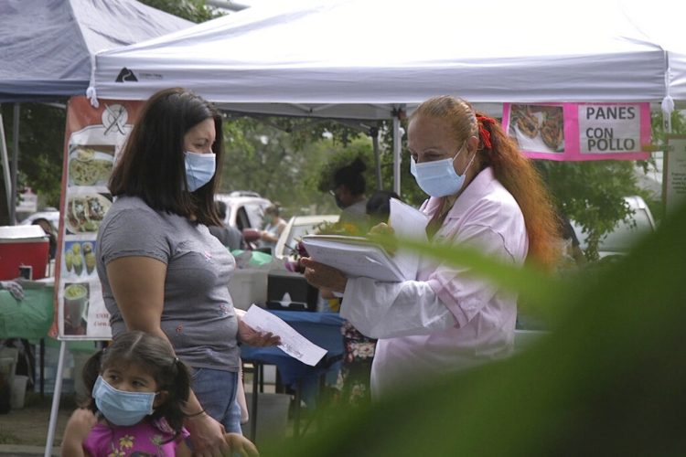 Una promotora de CASA, un grupo activista hispano, busca voluntarios latinos para probar una posible vacuna contra el COVID-19, en un mercado de Takoma Park, Maryland, el 9 de septiembre de 2020. Foto: Federica Narancio/AP.