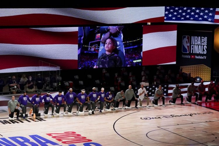 El 6 de octubre, integrantes de los Lakers de Los Ángeles se hincan durante el himno nacional antes del cuarto juego de las Finales de la NBA ante el Heat de Miami. Foto: John Raoux/AP.