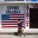 Una mujer con un niño pasa junto a un negocio de mensajería en el pueblo mayoritariamente indígena de Joyabaj, Guatemala. La mitad de lsus residentes dependen de las remesas. Foto: Moises Castillo/AP.