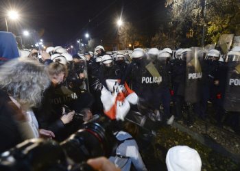 La policía arranca un cartel mientras manifestantes se concentran frente a la residencia del dirigente oficialista polaco Jaroslaw Kaczynski para protestar un fallo de la Corte Constitucional que endurece las leyes contra el aborto.  Foto: Czarek Sokolowski/AP.