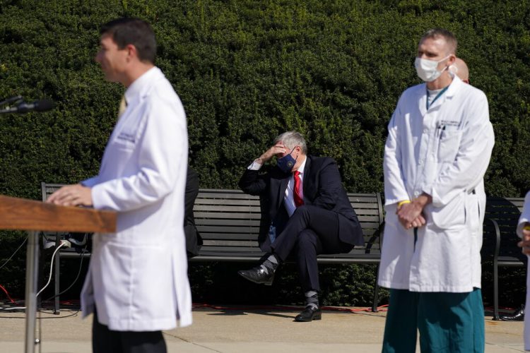 El jefe de despacho de la Casa Blanca Staff Mark Meadows (sentado, al centro) escucha mientras el médico del presidente Donald Trump, el doctor Sean Conley, habla frente a los reporteros frente al Centro Médico Militar Nacional Walter Reed, en Bethesda, Maryland, el domingo 4 de octubre de 2020. Trump pasó su segunda noche en ese hospital tras caer enfermo de coronavirus. Foto: Jacquelyn Martin/AP.