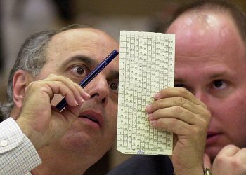 Dos abogados, uno de cada partido, certifican ocularmente la validez de una boleta en el condado de Palm Beach durante el reconteo de las elecciones presidenciales de 2000. Foto: Wilfredo Lee/AP/Archivo.