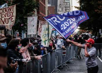 Un seguidor del presidente Trump ondea una bandera frente a un grupo de seguidores de Joe Biden en el exterior de un centro de escrutinio electoral en Filadelfia. Foto: Mario Cruz / EFE