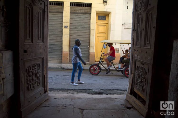 Unas personas pasan frente a unas puertas exteriores en La Habana. Foto: Otmaro Rodríguez.