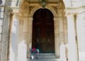 Un hombre revisa un dispositivo móvil sentado frente a una puerta exterior en La Habana. Foto: Otmaro Rodríguez.