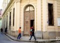 Unas personas pasan frente a una puerta exterior en La Habana. Foto: Otmaro Rodríguez.