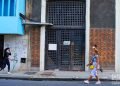 Unas personas pasan frente a una puerta exterior en La Habana. Foto: Otmaro Rodríguez.