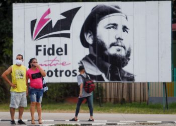 Algunos transeúntes caminan frente a una valla con la imagen de Fidel Castro en La Habana, el 25 de noviembre de 2020, día en que se conmemora el cuarto aniversario de la muerte del líder cubano. Foto: Yander Zamora / EFE.