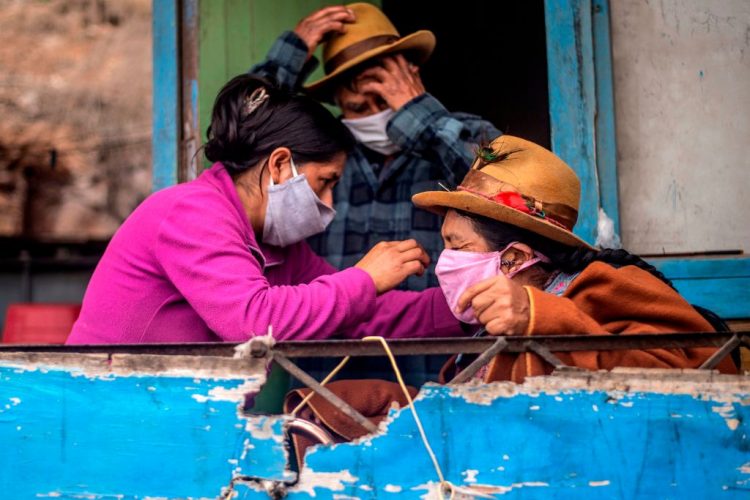 Una mujer le arregla la mascarilla a su madre en una localidad de Pamplona Alta en la periferia sur de Lima. Foto; Time.