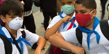 Tres niños se saludan antes de entrar a su escuela en La Habana, durante la pandemia de la COVID-19. Foto: Otmaro Rodríguez / Archivo.