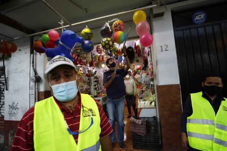 Trabajadores comienzan a cerrar su negocio después de una visita de funcionarios de seguridad pública municipal, quienes les exigen cumplir con la nueva orden estatal que requiere que los establecimientos no esenciales cierren a las 5 de la tarde para ayudar a disminuir la propagación del COVID-19 en Ecatepec, Estado de México, a las afueras de la Ciudad de México, el lunes 14 de diciembre de 2020.  Foto: Rebecca Blackwell/AP.