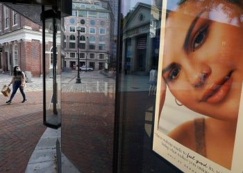 Una mujer carga una bolsa de compras mientras camina frente a una tienda de cosméticos cerca de Faneuil Hall. Foto:  Steven Senne/AP.