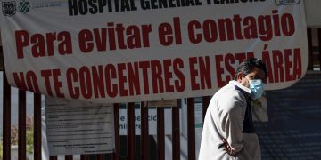 Un hombre camina frente a un letrero de advertencia de alto contagio de la COVID-19, en el Hospital General Tláhuac de Ciudad de México. Foto: José Méndez / EFE.