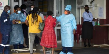 Una trabajadora de salud revisa la temperatura de una paciente en la entrada de la sala de emergencias del Hospital Académico Steve Biko, en Pretoria, Sudáfrica, el lunes 11 de enero de 2021. Foto: AP/Themba Hadebe.