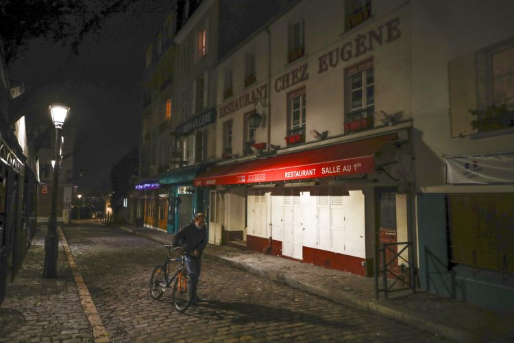 Un hombre con su bicicleta frente a varios restaurantes cerrados en Montmartre, durante el toque de queda impuesto en París por la pandemia de coronavirus. Foto: Michel Euler/AP.
