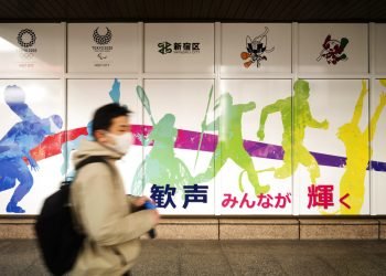 Un hombre con mascarilla pasa frente al edificio de oficinas municipales de Shinjuku, en el que se promocionan los Juegos Olímpicos reprogramados para mediados de este año, en Tokio, el viernes 29 de enero de 2021. Foto: AP/Hiro Komae.