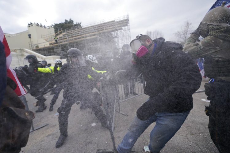 Simpatizantes de Donald Trump buscan cruzar por la fuerza una valla de la policía que rodea el Capitolio en Washington, el miércoles 6 de enero de 2021. Foto: Julio Cortez / AP.