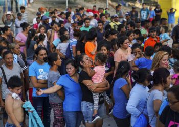 Migrantes, muchos de ellos devueltos a México por la política migratoria del entonces presidente de Estados Unidos Donald Trump, esperan en final para recibir alimentos en un campamento en el puente internacional en Matamoros, México. Foto: Veronica G. Cárdenas/Ap/ archivo.