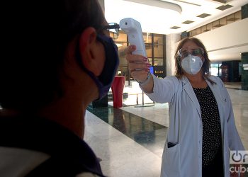 Una doctora toma la temperatura a una persona en el hotel Melià Habana, una de las instalaciones que ofrece paquetes turísticos para el aislamiento de viajeros internacionales en la capital cubana. Foto: Otmaro Rodríguez.