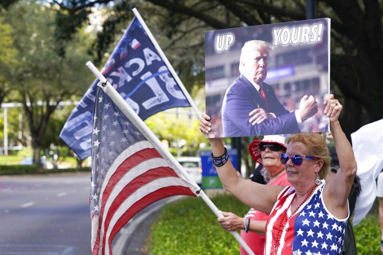 Seguidores de Donald Trump ondean banderas y letreros a los conductores que pasan frente al centro de convenciones en la Conferencia de Acción Política Conservadora el sábado 27 de febrero de 2021 en Orlando, Florida. Foto: AP/John Raoux.