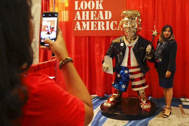 Una mujer se toma una foto junto a una estatua dorada de Donald Trump en la Conferencia Conservadora de Acción Política el 26 de febrero de 2021 en Orlando, Florida. Foto: Sam Thomas/AP.