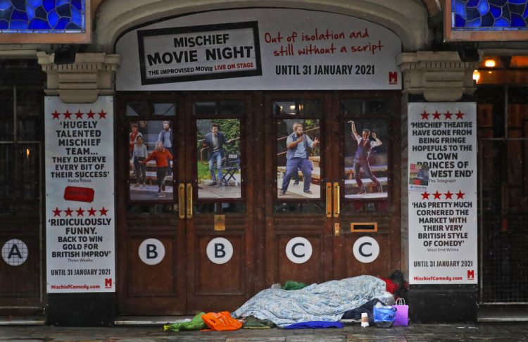 Una persona sin hogar duerme a la entrada de un teatro cerrado por la pandemia del coronavirus, en Londres, el 8 de febrero de 2021. Foto: Frank Augstein/Ap.