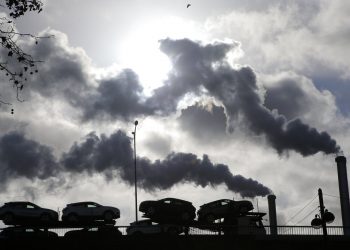 Humo saliendo de una fábrica mientras un camión cargado de autos pasa por un puente en París, Francia.  Foto: Michel Euler/Ap/ Archivo.