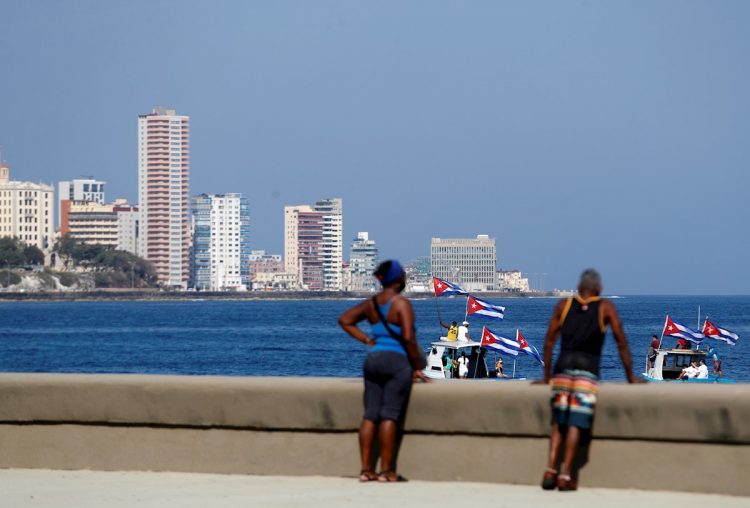 Personas observan las embarcaciones que participa en la regata contra el bloqueo, en el malecón de La Habana. Foto: Yander Zamora/Efe.