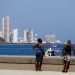 Personas observan las embarcaciones que participa en la regata contra el bloqueo, en el malecón de La Habana. Foto: Yander Zamora/Efe.