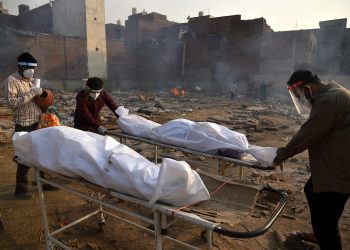 Un cuerpo es preparado para los últimos ritos en piras funerarias para las víctimas de COVID-19, en un campo de cremación improvisado en Nueva Delhi, la India, el 1 de mayo de 2021. Foto: Idrees Mohammed / EFE.