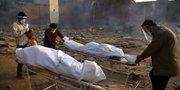 Un cuerpo es preparado para los últimos ritos en piras funerarias para las víctimas de COVID-19, en un campo de cremación improvisado en Nueva Delhi, la India, el 1 de mayo de 2021. Foto: Idrees Mohammed / EFE.