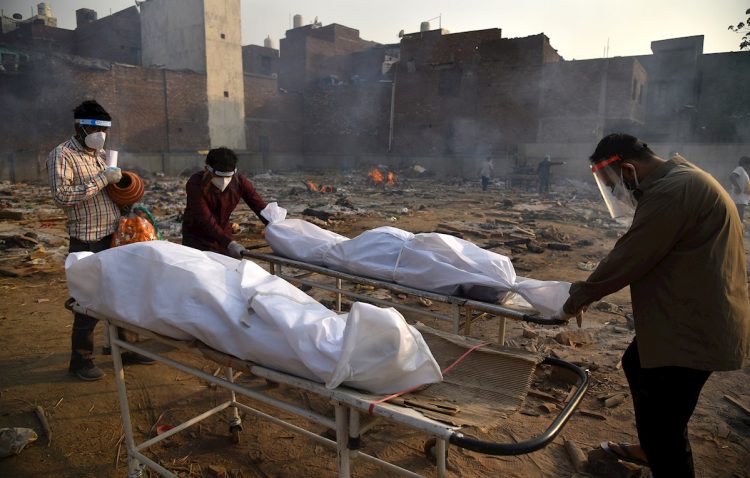 Un cuerpo es preparado para los últimos ritos en piras funerarias para las víctimas de COVID-19, en un campo de cremación improvisado en Nueva Delhi, la India, el 1 de mayo de 2021. Foto: Idrees Mohammed / EFE.