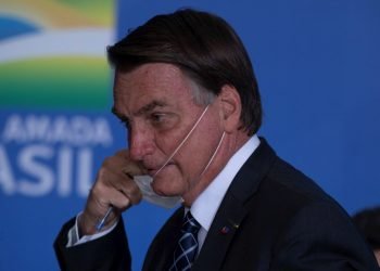 El presidente de Brasil, Jair Bolsonaro, se quita una mascarilla en un acto en el Palacio do Planalto, en la ciudad de Brasilia. Foto: Joédson Alves / EFE.