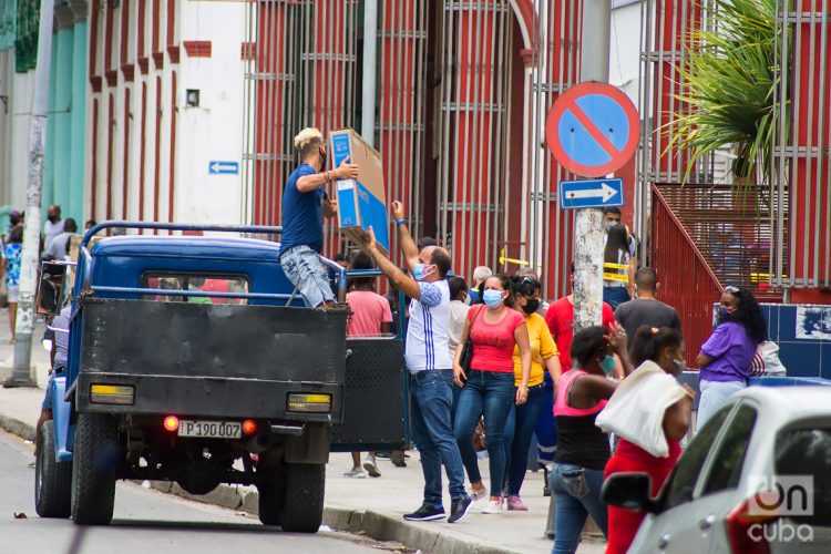 Personas cargan mercancías compradas en Moneda Libremente Convertible, en el centro comercial Carlos III, en La Habana. Foto: Otmaro Rodríguez.